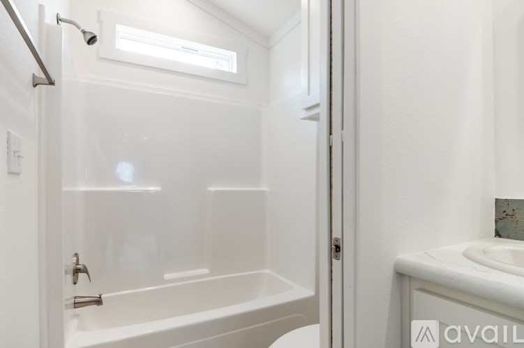 A white bathroom with a glass shower door and a white sink.