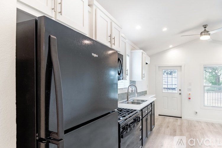 A black fridge in a kitchen with white cabinets.