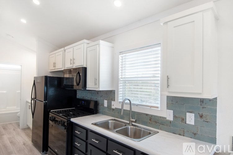 A kitchen with black appliances and white cabinets.