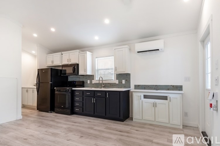 A kitchen with black appliances and white cabinets.