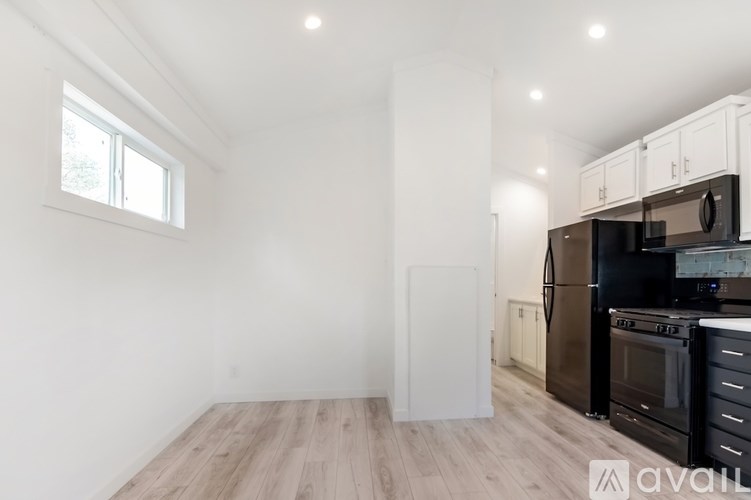 A kitchen with black appliances and wooden floors.