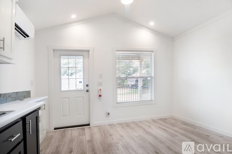 A kitchen with a white door and a window with blinds.