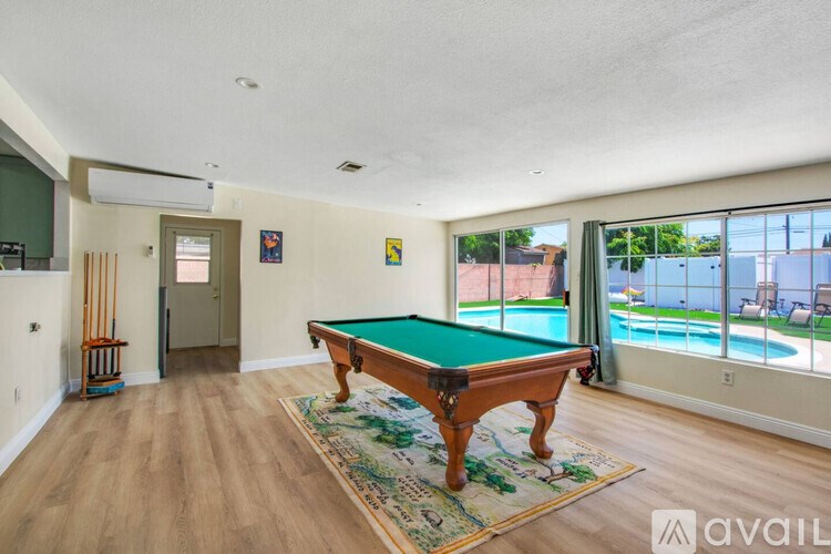 A room with a pool table and a view of the pool.