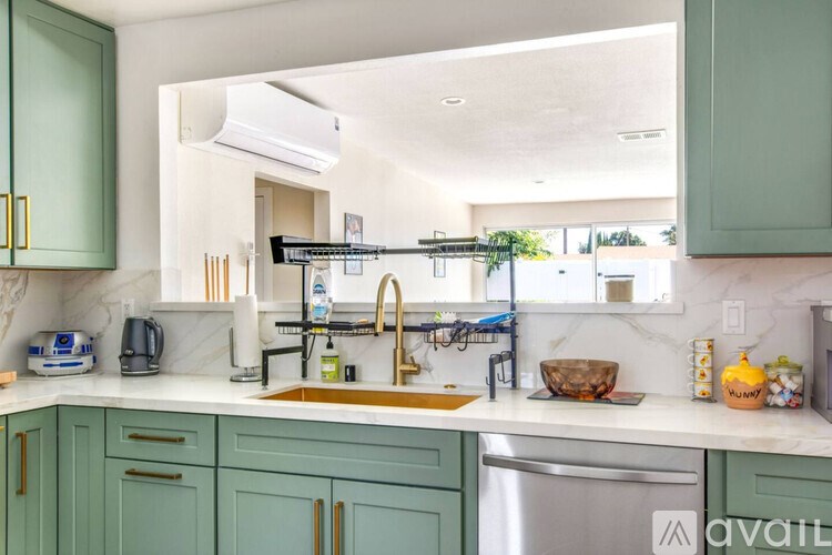 A kitchen with green cabinets and a marble countertop.