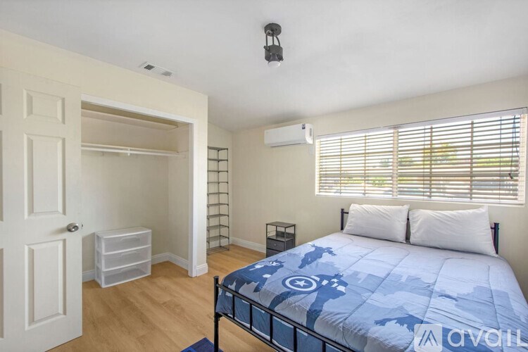 A bedroom with a bed, nightstand, and window with blinds.