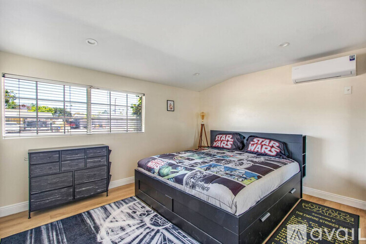 A bedroom with a black bed and a Star Wars comforter.