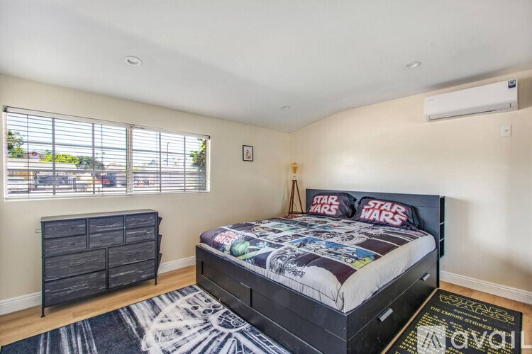 A bedroom with a black bed and a Star Wars comforter.