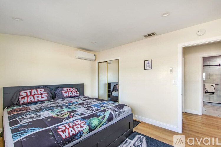 A bedroom with a Star Wars themed bedspread.