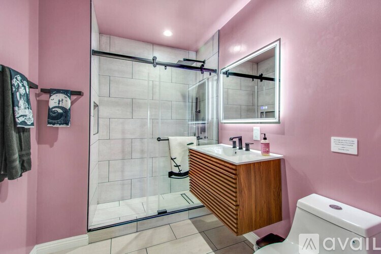 A bathroom with pink walls and a wooden vanity.