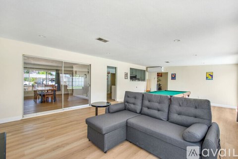A living room with a grey sofa and a billiard table.