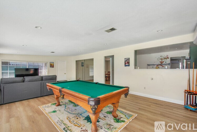 A pool table in a room with a couch and a window.