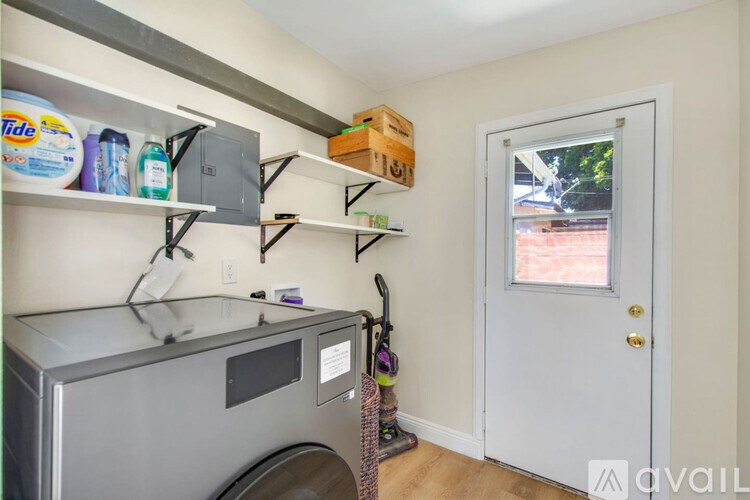 A laundry room with a washer and dryer, shelves, and a door leading outside.
