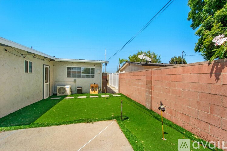 A backyard with a green lawn and a concrete patio.