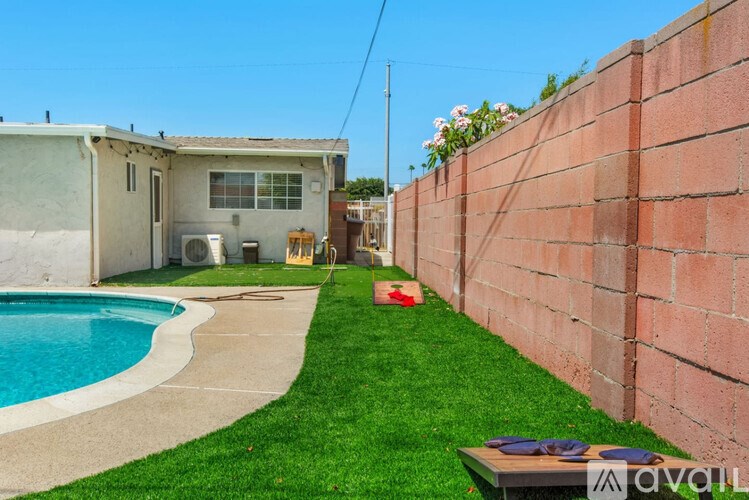 A backyard with a pool and a brick wall.