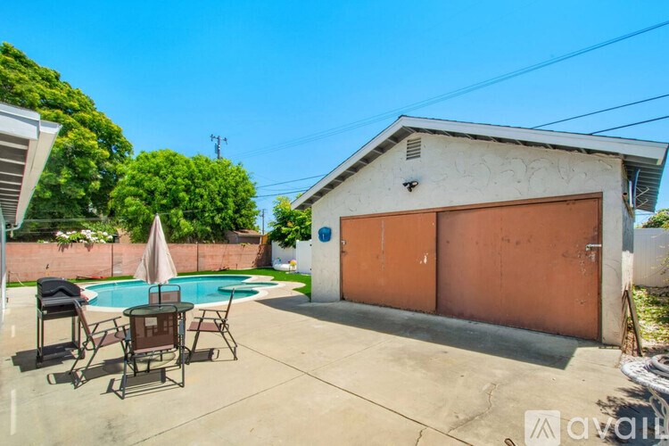 A patio with a table and chairs is in front of a house.