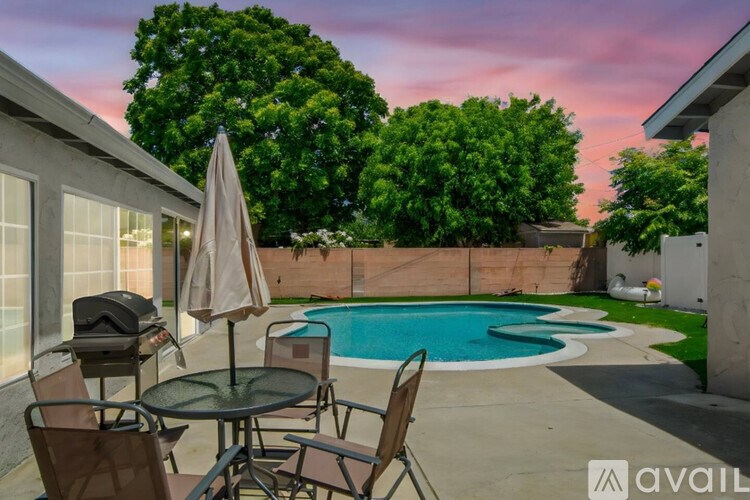 A patio with a table and chairs overlooking a pool.