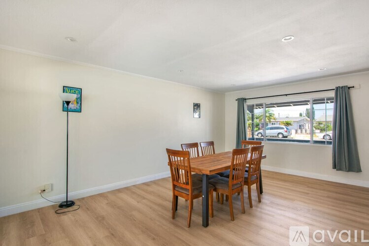 A room with a wooden table and chairs and a sign on the wall.