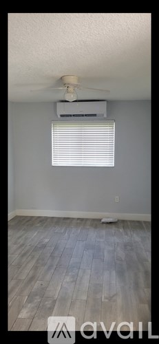 A room with a ceiling fan and a window with blinds.