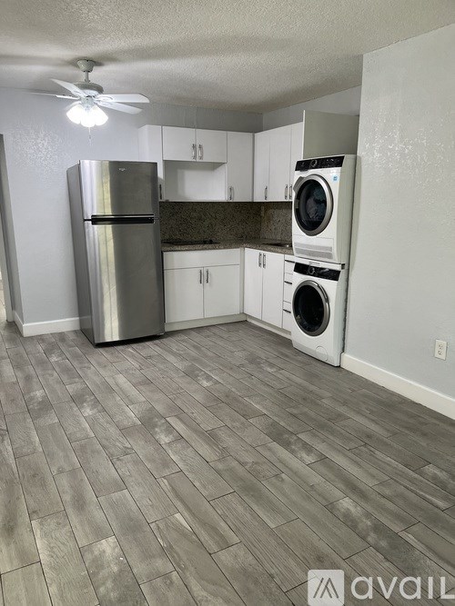 A kitchen with a refrigerator, washer and dryer.