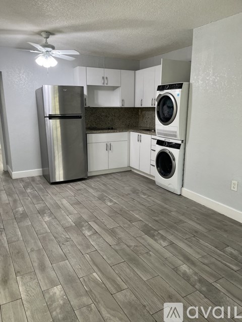 A kitchen with a refrigerator, washer and dryer.