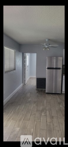 A room with a ceiling fan and a refrigerator.