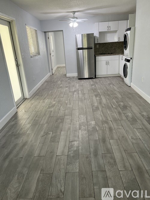 A kitchen area with a refrigerator, washing machine, and cabinets.