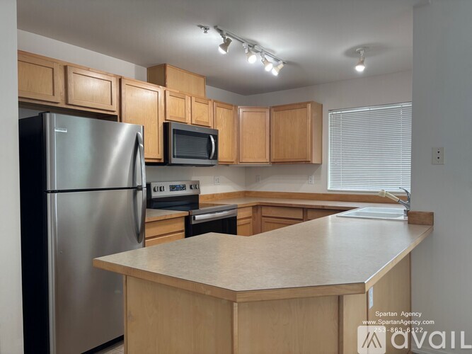 A kitchen with wooden cabinets and a stainless steel refrigerator.