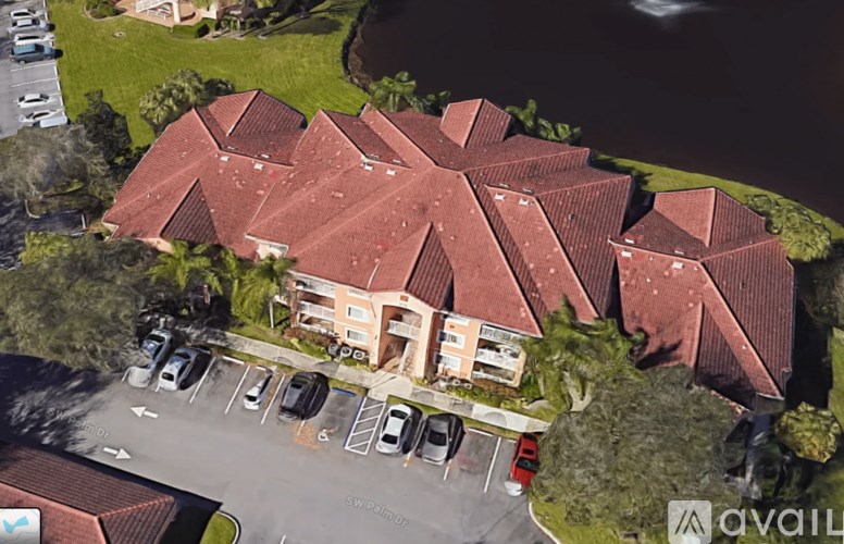A building with a red roof is surrounded by a parking lot.