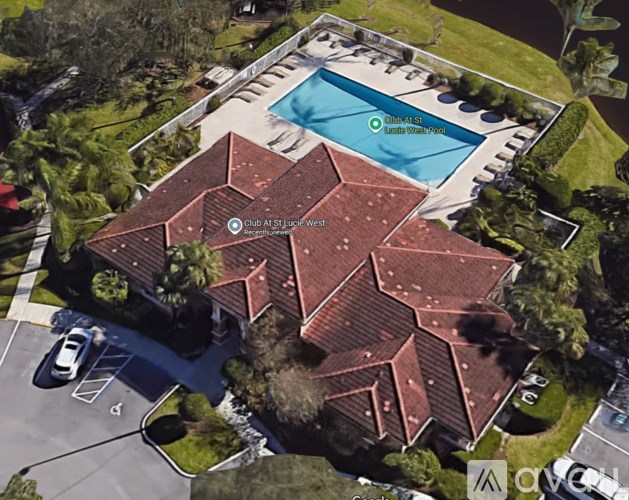 A clubhouse with a pool is surrounded by trees.