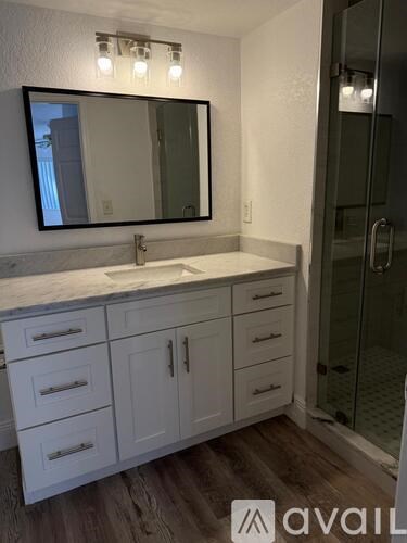 A bathroom with a sink, mirror, and cabinets.