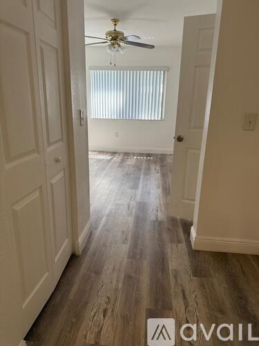 A hallway with a fan and wooden floors.
