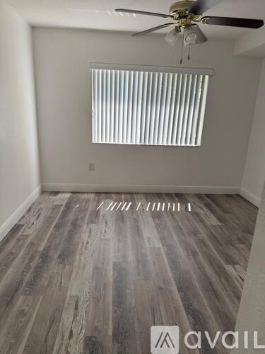 A room with a ceiling fan and a window with blinds.