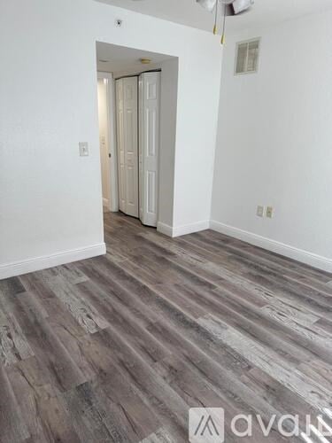 A room with wood flooring and a white door.