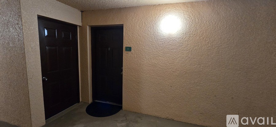A hallway with a black door and a light on the wall.