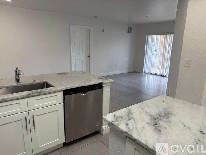 A kitchen with white cabinets and a marble countertop.
