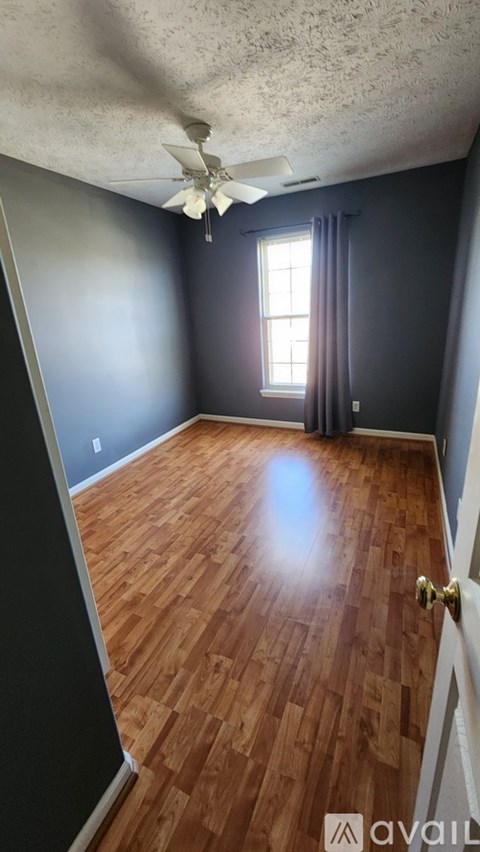 A room with wooden flooring and a ceiling fan.