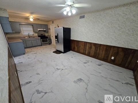A kitchen with a black fridge and wooden walls.