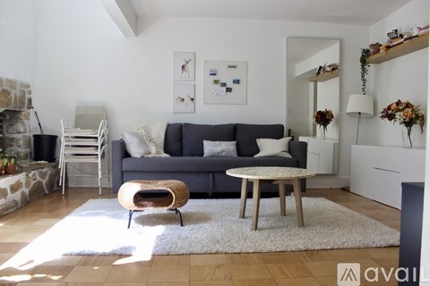 A living room with a grey couch, a white table, and a white rug.