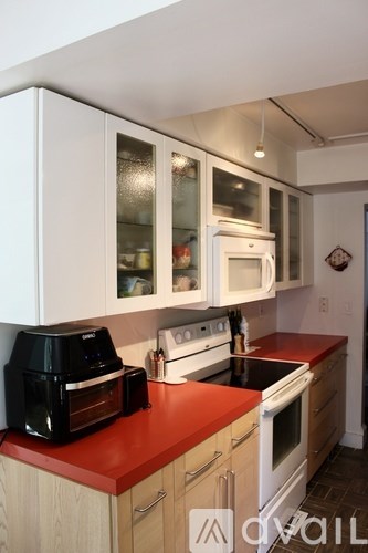 A kitchen with a red counter top and white cabinets.