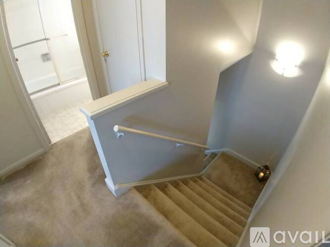 A staircase with a beige carpet and a grey wall.