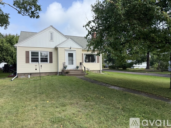 A house with a white door and windows is surrounded by a grassy lawn.