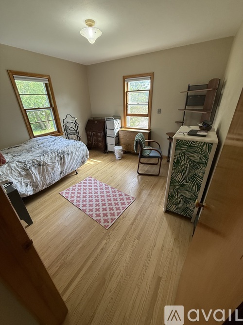 A bedroom with a bed, chair, and a dresser with a mirror.