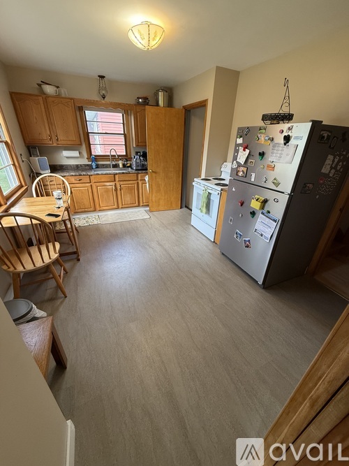 A kitchen with a refrigerator on the right and a dining table with chairs on the left.
