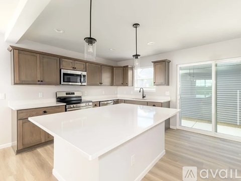 A modern kitchen with a white island and wooden cabinets.