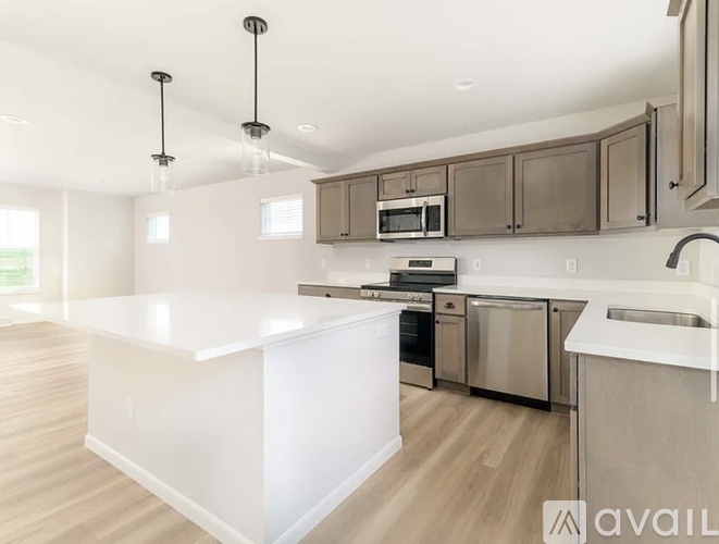 A modern kitchen with a white countertop and stainless steel appliances.