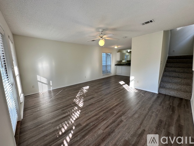 A spacious room with wooden flooring and a ceiling fan.