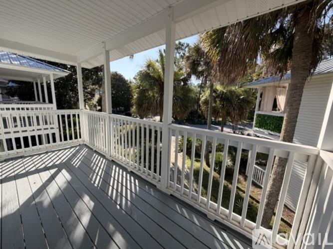 A white deck with a railing and trees in the background.
