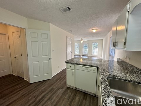 A kitchen with white cabinets and a granite countertop.