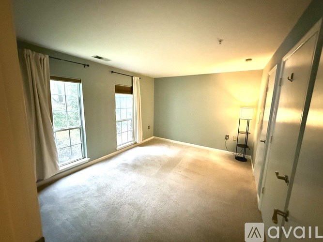 A room with a carpeted floor, a window with curtains, and a door.