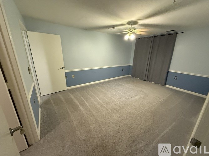 A room with a ceiling fan and carpeted floor.